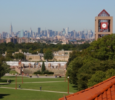 Photograph of the Queens College library clock tower with the Manhattan skyline in the distance.